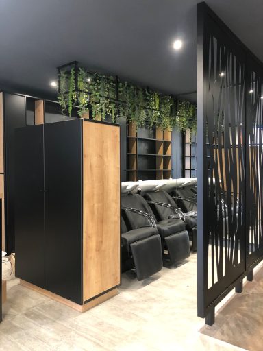 Intérieur moderne avec fauteuils de massage, murs noirs et verdure décorative.