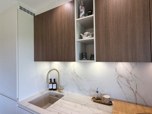 Cuisine moderne avec des placards en bois, un évier en marbre et un éclairage doux.