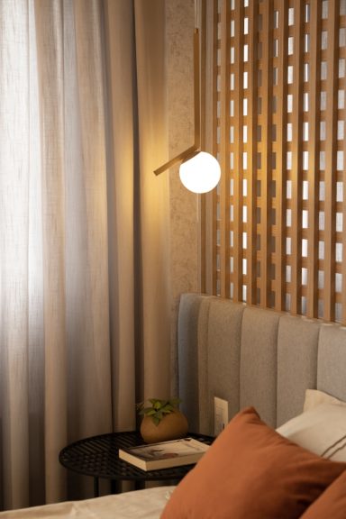 Chambre élégante avec une lampe moderne, rideaux clairs et tête de lit grise.