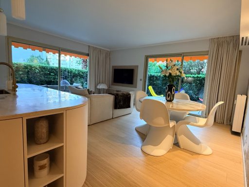 3 pièces le Wiosna, Cannes Intérieur d'un salon moderne avec une table à manger, des chaises, et des fenêtres lumineuses.