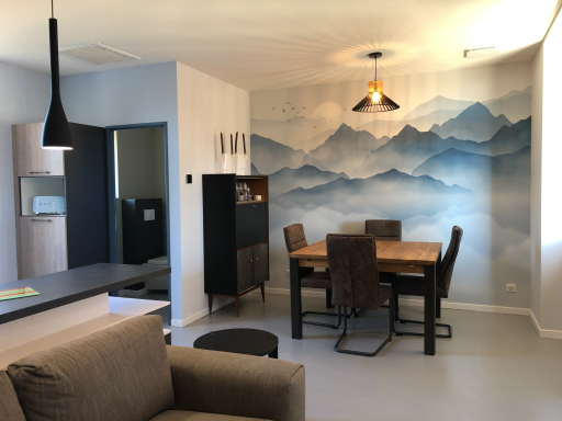 Salon moderne avec mur en papier-peint panoramique de montagnes et coin repas en bois.