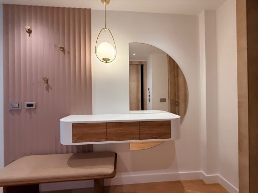 Intérieur moderne avec un meuble en bois, un miroir circulaire et des murs texturés.
