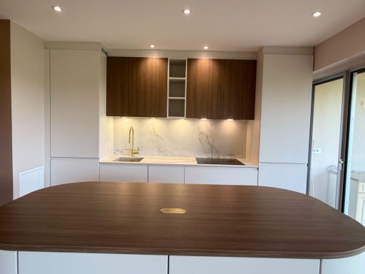 Cuisine moderne avec îlot central, meubles clairs et éclairage doux.