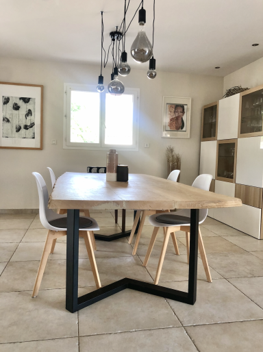 Salle à manger moderne avec une table en frêne et pied métal noir.