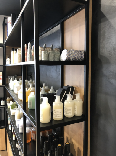 Étagère noire avec divers flacons de produits de soin et de beauté des cheveux.