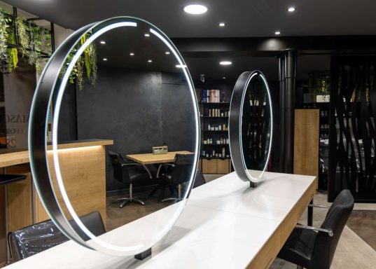 Deux miroirs ronds rétroéclairés sur un comptoir moderne dans un espace intérieur élégant.