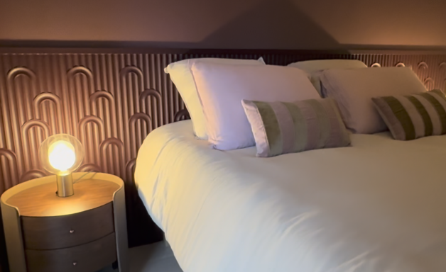 3 pièces le Wiosna, Cannes Chambre avec lit, coussins décoratifs et lampe de chevet sur une table ronde.
